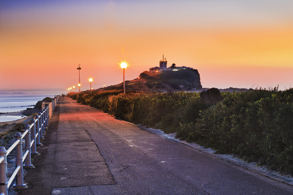 Nobbys Lighthouse at sunset on Nobbys Head in Newcastle with golden sky and ocean view
