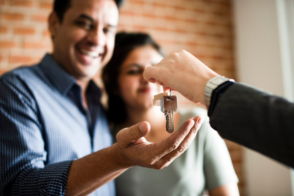 Excited couple receiving the keys to their new home from a professional in a suit