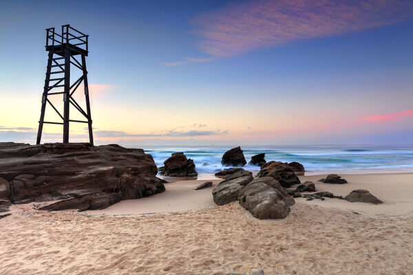 The Shark Tower and jagged rocks at Redhead Beach, NSW with a pastel sunset sky