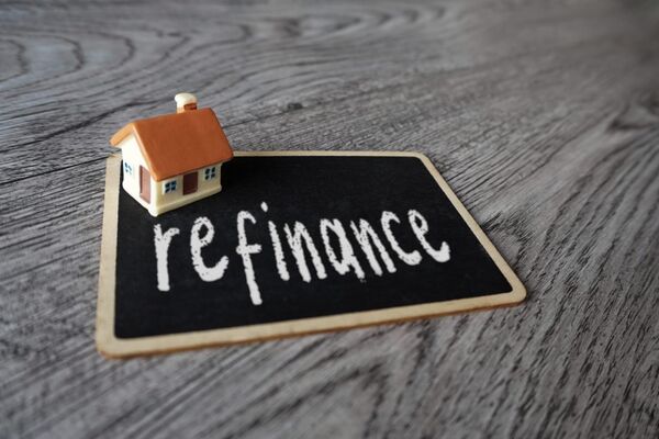 Small toy house next to wooden blocks spelling Refinance