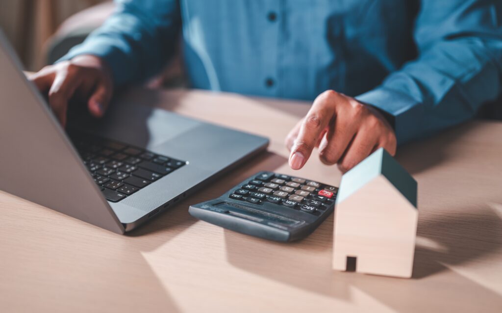 Model house, calculator, and financial documents representing property investment planning