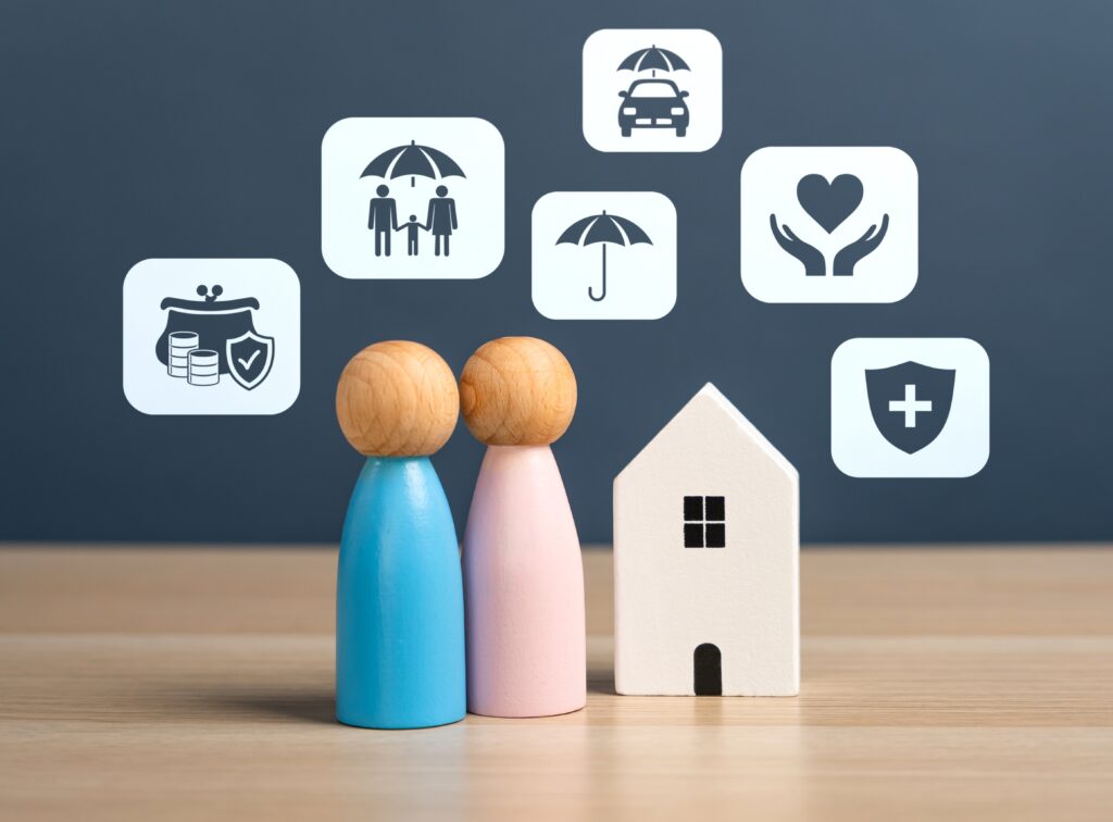 Miniature wooden figures of a married couple standing next to a small model house