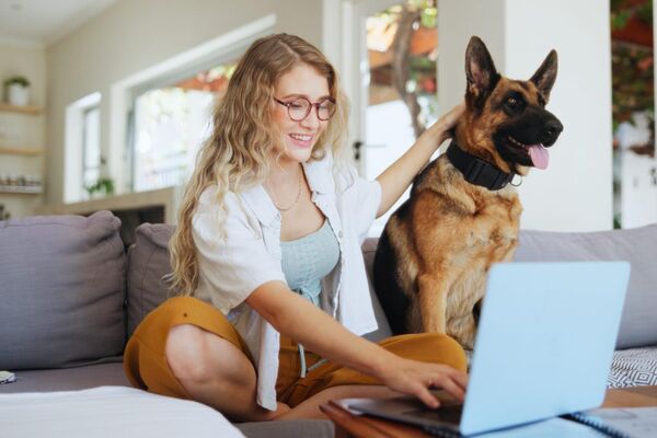 Woman relaxing on sofa with her dog and laptop