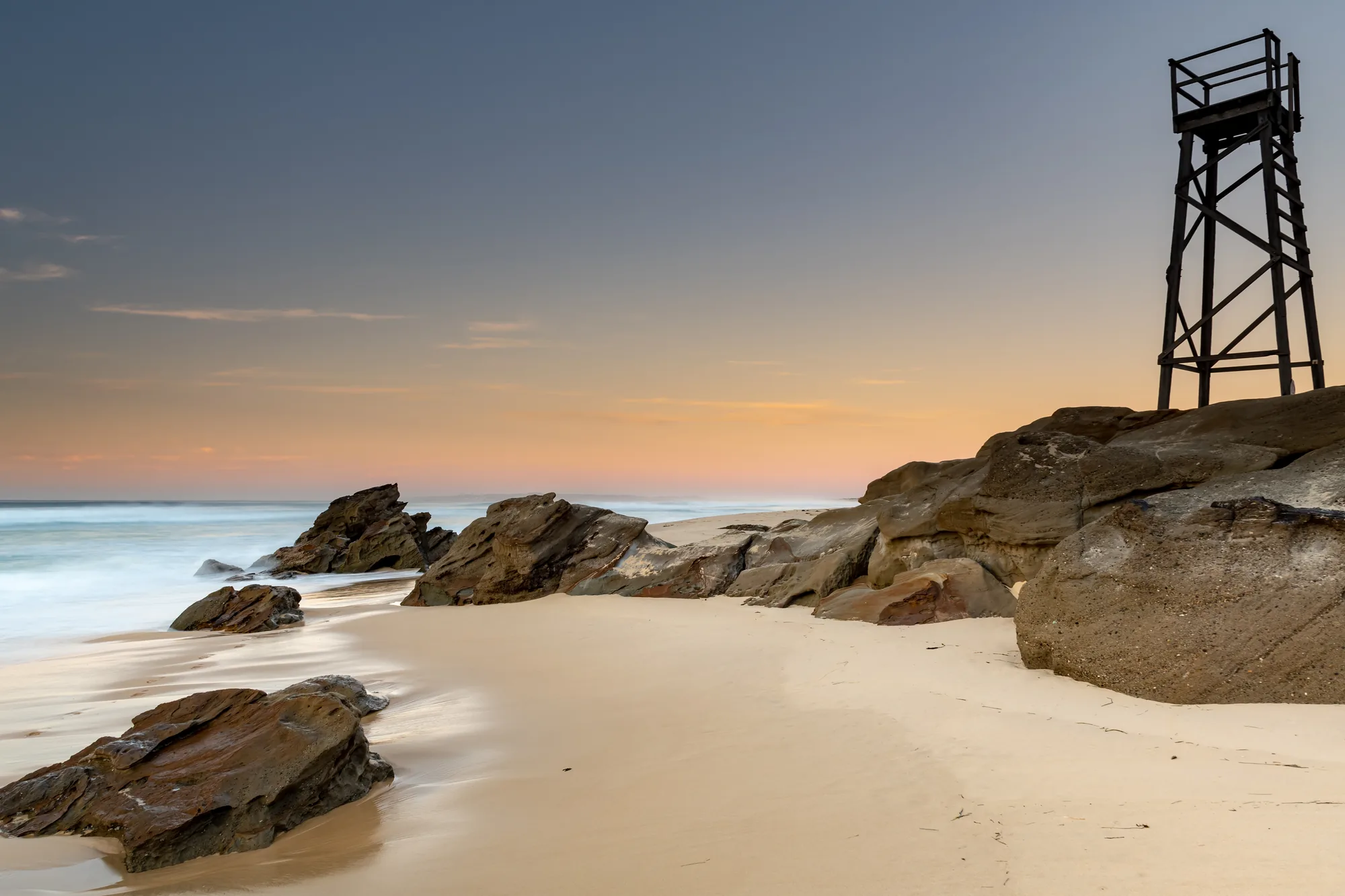 Rocky beach and lookout tower on the Hunter coastline at dusk